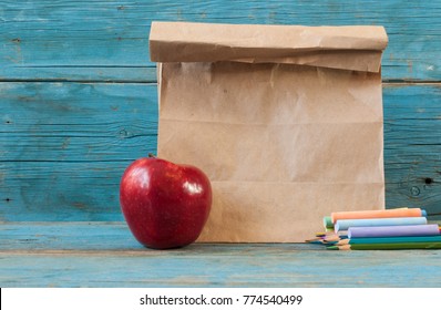 School lunch. Brown paper bag and a red apple on wooden background. - Powered by Shutterstock