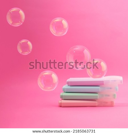 School markers in rainbow pastel colors with transparent balloons. Pink dreamy background scene. Supplies for classroom concept. Fantasy neon aesthetic design idea. Education student table