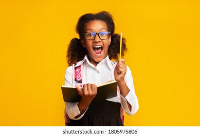 School Nerd. Excited Black Schoolgirl Holding Pencil Having Idea Standing Over Yellow Background. Studio Shot