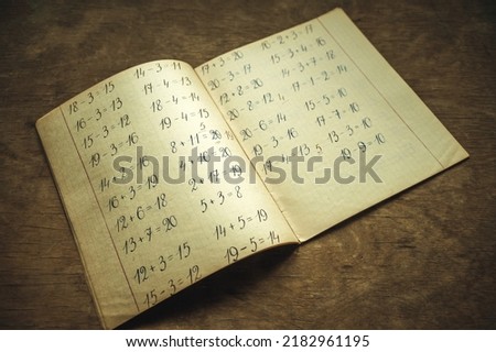 A school notebook with math notes on a wooden table. Vintage notebook with numbers written with a fountain pen. I'm going to school soon. Old school.Photo in vintage style.