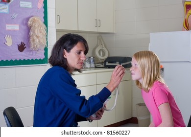 School nurse checking temperature of student patient.