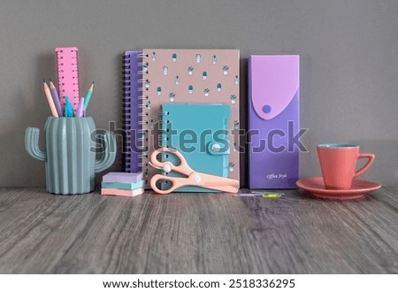 School and office accessories. A notebook, a notepad, pencils, stickers and a cup of coffee on the desk. Back to school. Stationery on a gray background.