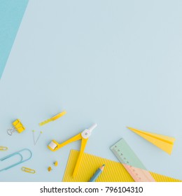 School or office background with stationery, notebook paper, keyboard, crayon, pen, ruller paper clip on blue and yellow colors. Flat lay.