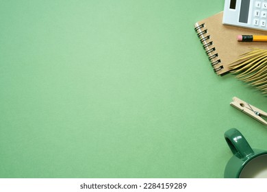 School office supplies  notebook  calculator  pencil  cup milk green desk background  flat lay  top view  copy space