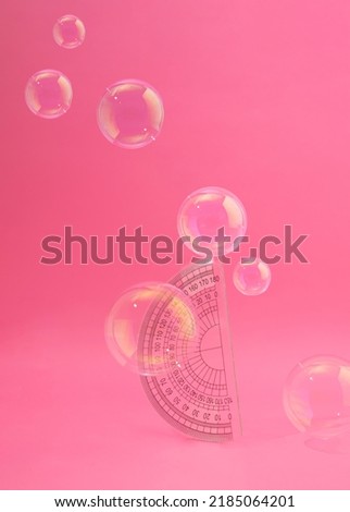 School protractor flying with transparent balloons. Pink dreamy background scene. Supplies for classroom learning concept. Fantasy neon aesthetic design idea. Education student table