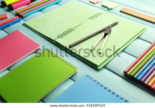 School set with notebooks, divider and colored\
pencils on wooden blue\
background