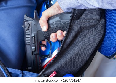 School shootings, gun control, bullying and gun violence. Social issues symbolic image. A child pulls out a 9mm pistol from a school backpack.