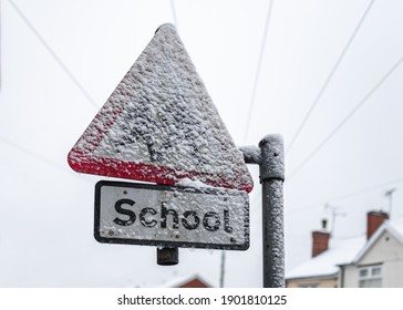 School sign covered in sleet crossing schools closed due to snow severe weather shut down warning freezing icy frozen heavy snowfall