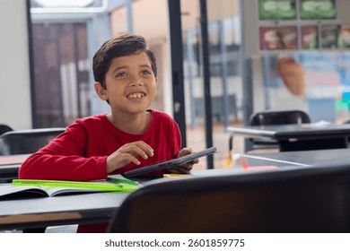 In school, smiling boy using tablet in classroom, engaging with technology, copy space. Education, learning, digital, childhood, interactive