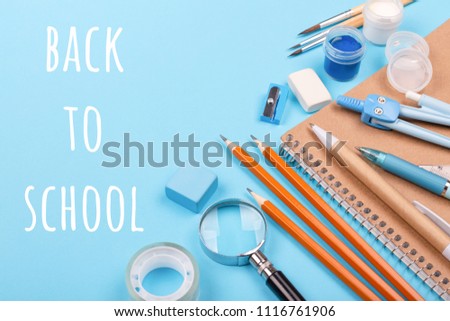School stationary on blue background with inscription BackTo School. Notebook, pens, pencils and other tools.