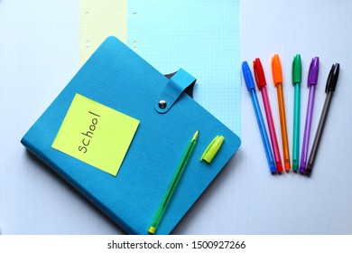 Сomposition of school stationery: colored pens, blue copybook and yellow pen