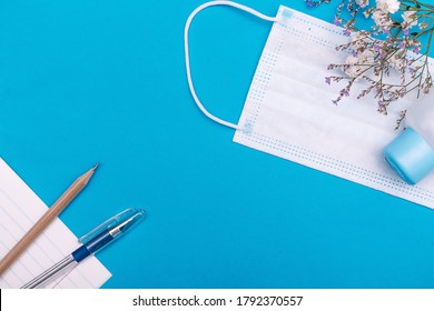 School Stationery Supplies,flowers, Protective Face Mask And Hand Sanitizer Antiseptic On Blue Background.Back To School During The Coronavirus Pandemic Concept.New Normal Concept.Copy Space,flat Lay