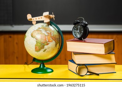 School still life with books, globe, airplane, magnifying glass, alarm clock. Chalk board to write background.