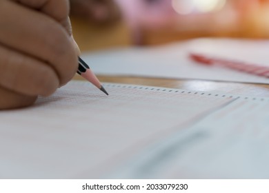 School Student Hands Taking Exams, Writing Examination Holding Pencil On Optical Form Of Standardized Test With Answers Sheet Doing Final Exam In Classroom. Education Assessment Concept. Soft Focus