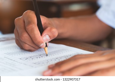 School student is taking exam and writing answer in classroom for education test concept