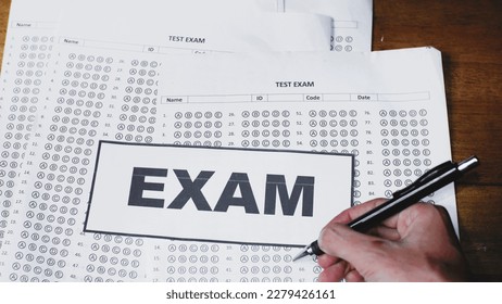 School students doing final exams. Asian hands doing the exam on multiple choice paper. Selective focus.