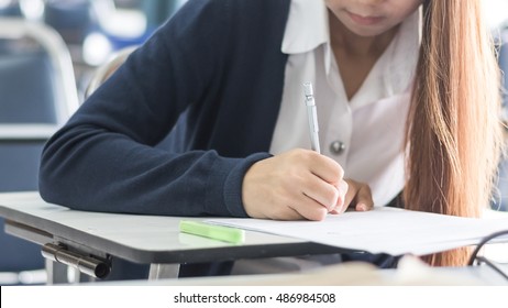 School Student's Taking Exam Writing Answer In Classroom