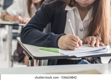 School student's taking exam writing answer in classroom for education and literacy concept