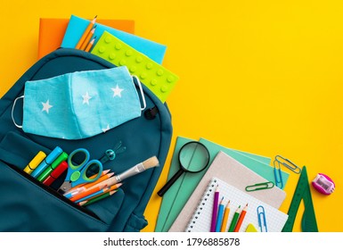 School supplies, blue backpack medical mask yellow background. Back to school, pandemic coronavirus concept, flat lay.Horizontal. Selective focus. View from above. Copy space. - Powered by Shutterstock