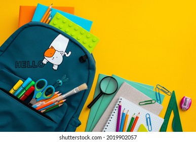 School supplies, blue backpack medical mask yellow background. Back to school, pandemic coronavirus concept, flat lay.Horizontal. Selective focus. View from above. Copy space.