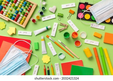 School Supplies And Coronavirus Spread Prevention Measures Flat Lay. Back To School 2021, Covid 19 Days. Rapid Self Test, Protective Medical Mask And Stationery On Green Background, Top View