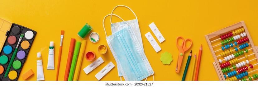 School Supplies And Coronavirus Spread Prevention Measures Flat Lay. Back To School 2021, Covid 19 Days. Rapid Self Test, Protective Medical Mask And Stationery On Orange Color Background, Top View