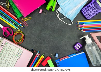 School Supplies And COVID 19 Prevention Items. Top View Frame On A Chalkboard Background. Back To School During Pandemic Concept.