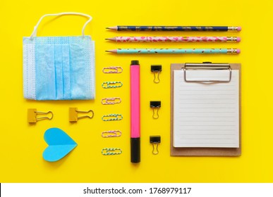 School supplies flatlay on yellow background. Clip board, paper clips, notebook, marker, paper heart, pen, clamp, fase mask. Back to school 2020. Online education. School banner. Geometric composition - Powered by Shutterstock - Get 15% off with code: PIKWIZARD15