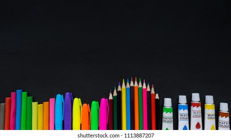 School supplies mockup on blackboard background with copyspace. Bright multicolored, pencils, pens, scissors, notepads, letters, figures, brushes, paints, clamps, eraser and other stationery
