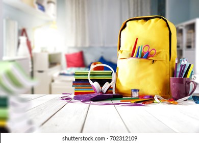 School supplies on a wooden table in a warm interior - Shutterstock ID 702312109