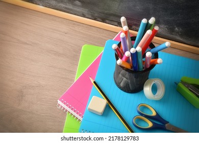 School supplies with pen with markers on notebooks with tools on wooden desk and blackboard. Elevated view. Horizontal composition. - Shutterstock ID 2178129783