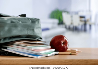 School supplies and schoolbag on wooden school desk. Blurred classroom background and copy space for school stuff and stationery on wooden desk.  - Powered by Shutterstock