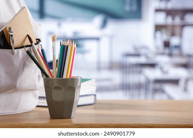 School supplies and schoolbag on wooden school desk. Blurred classroom background and copy space for school stuff and stationery on wooden desk.  - Powered by Shutterstock