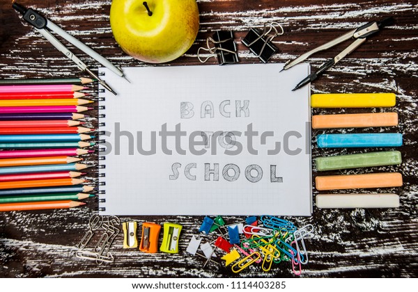School supplies side\
border on white wooden chalkboard background. Top view of school\
supplies - Back to school concept - word in notebook. education\
background