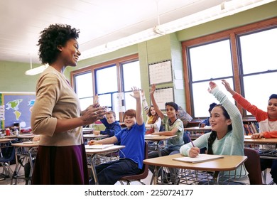 School, teacher and children raise their hands to ask or answer an academic question for learning. Diversity, education and primary school kids speaking to their woman educator in the classroom. - Powered by Shutterstock