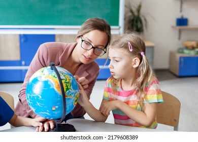 School teacher and children study the globe in elementary college. Lesson for kids in classroom. Woman teaching primary students ecological responsibility, environmentalism. After-school activities - Powered by Shutterstock