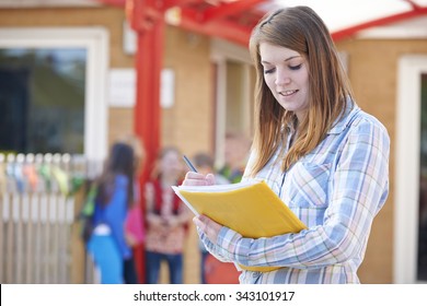 School Teacher Making Notes In Playground