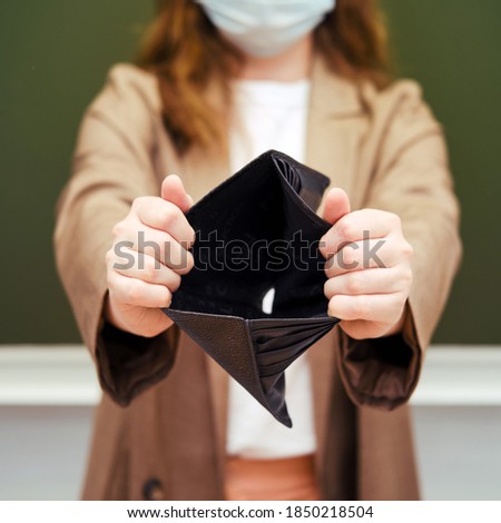 School teacher in a medical mask with a hole in the wallet with no money