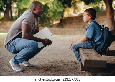 School teacher motivating a young primary school kid outside class. Child mentor talking to a troubled school boy. Support and encouragement for a student in elementary school. - Powered by Shutterstock