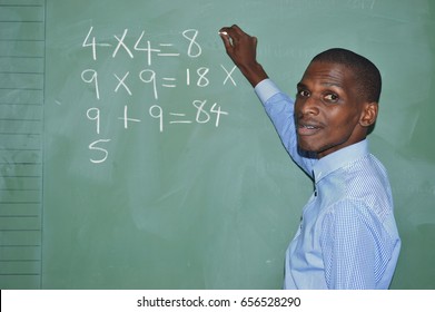 School Teacher Writing On A Board In Class