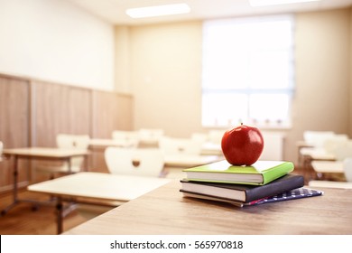 School teacher's desk with stack of books and apple