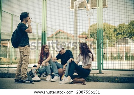School teenagers consuming drugs, alcohol and tobacco on the school property while having fun and talking.