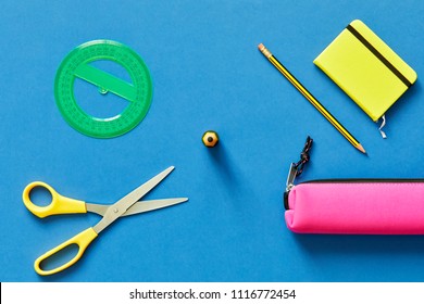 School Tools Such As Yellow Scissors, Pencil, Ruler, Eraser, And Pencil Case, Over A Blue Flatlay In Blue From Above