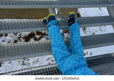 School Trip, Falling From Metal Stairs In Winter Glides Dangerously. A Little Boy In Winter Boots Fell And Lay Injured On The Stairs. Legs Broken Twisted Danger Of Falling, Stun, Metal Staircase