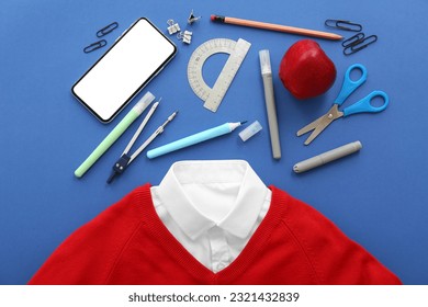 School uniform with fresh red apple, mobile phone and different stationery on blue background - Powered by Shutterstock