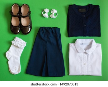 School Uniform (skirt, Blouse, Jacket, Shoes, Bows, Socks) On A Green  Background. Top View.