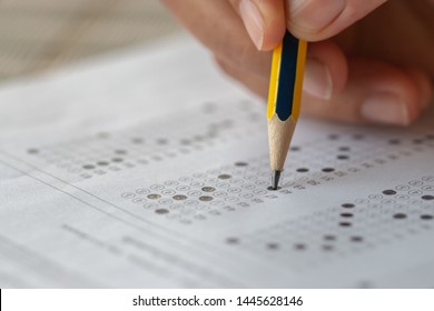 School Or University Students Hands Taking Exams, Writing Examination Room With Holding Pencil On Optical Form Answers Paper Sheet On Desk Doing Final Test In Classroom. Education Assessment Concept