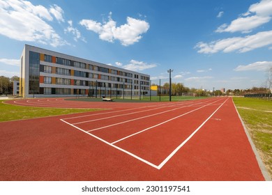 In the school yard: an red artificial turf running track and a soccer field with football goals