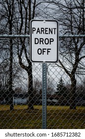 School Zone Parent Drop Off Sign In Front Of A Fence And  Trees And Houses In The Background