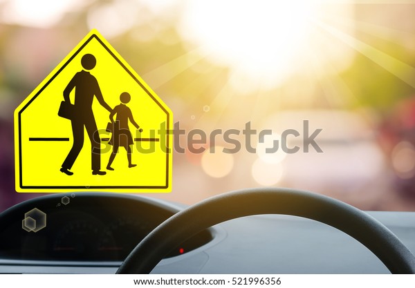 School zone warning sign and inside car view\
,steering wheel on blur traffic road with colorful bokeh light\
abstract background. Copy space of transportation and travel\
concept. Vintage tone\
color.